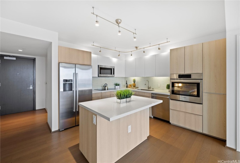 The kitchen boasts ample space with beautiful quartz counters, an abundance of cabinets and stainless steel Bosch appliances.