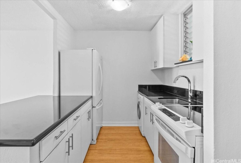 Kitchen island with granite counters and the washer is a Whirlpool under the counter - dryer by Bosch located on the lanai in built in cabinets.