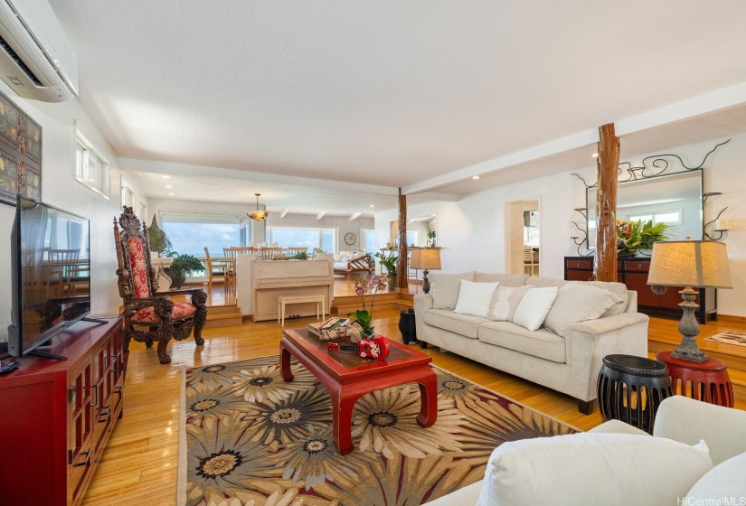 A spacious sunken living room with bamboo floors, native ohia poles and ocean views.