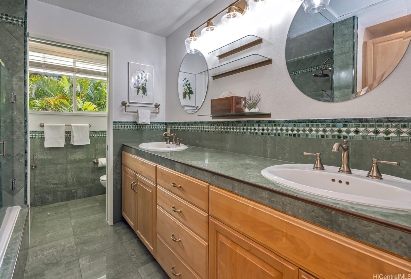 The primary bath is beautifully tiled, with lots of cabinetry space and dual sinks.