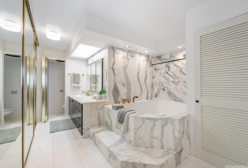 Primary ensuite featuring a soaking tub, ample closet space, separate water room and washer/dryer behind the shutters doors.