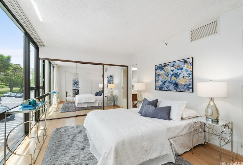 Floor-to-ceiling windows enhance the spaciousness of the primary bedroom suite with a large closet that features built-in drawers.