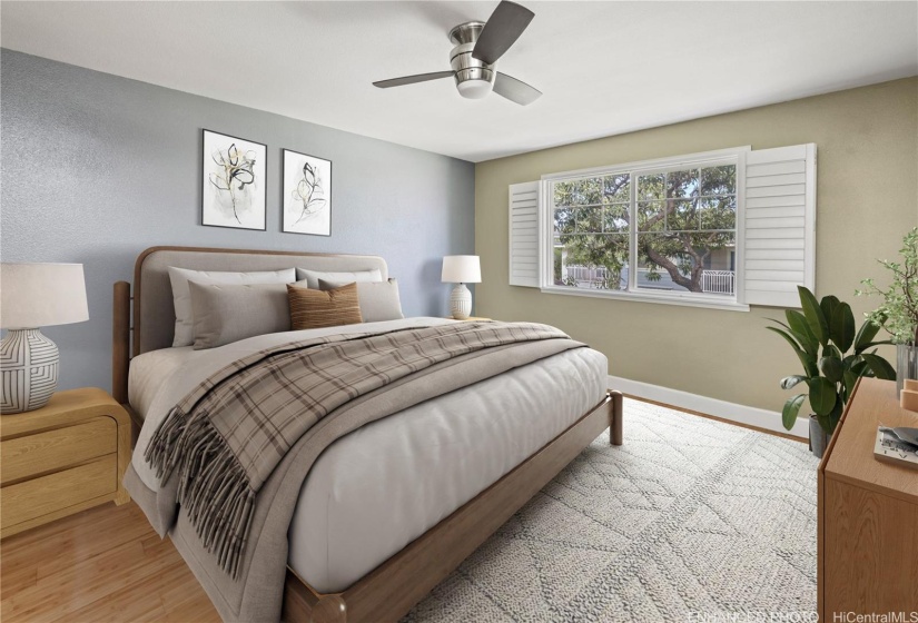 Primary bedroom has wood laminate floors & plantation shutters.   Virtually staged/enhanced.