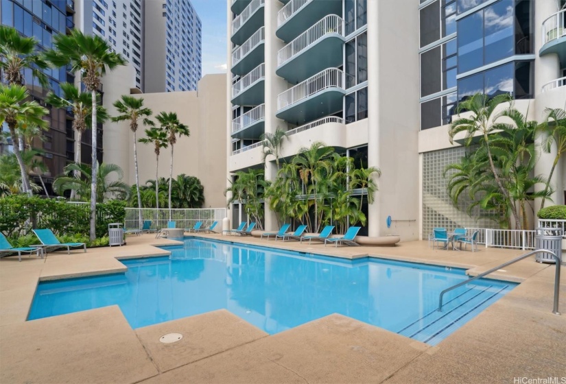 Spacious pool area surrounded by lush greenery and a private park.