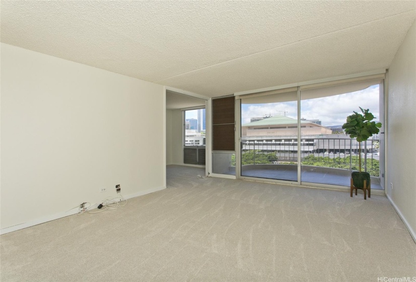 Unstaged living room with freshly retiled lanai. Perfect wall for an entertainment console (cable outlet is right there).