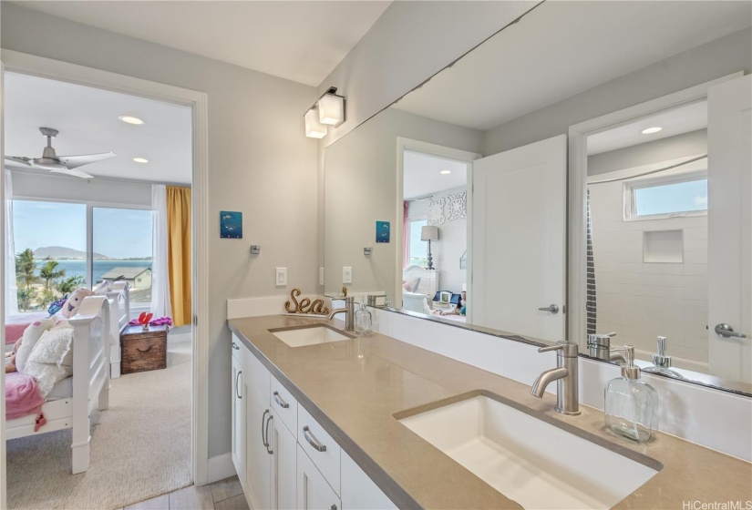 Jack and Jill bathroom with entry to connecting bedroom that has breathtaking Kaneohe Bay views.  Double sink is convenient for sharing. There is a tub and toilet that opens behind the sinks.  See the mirror reflection.