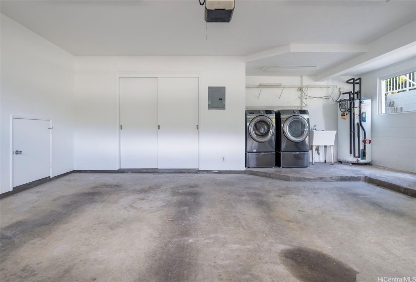 Spacious garage with full size washer dryer and additional storage space.