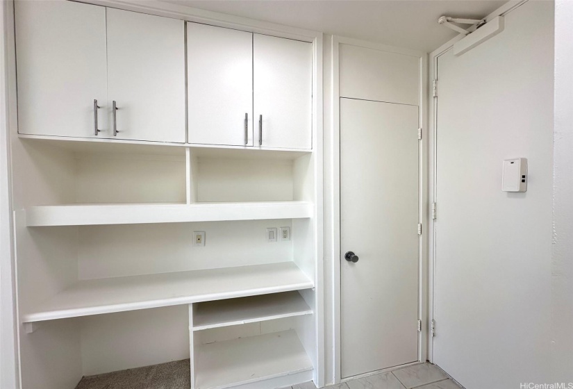 Entry area with utility closet and extra cabinet space and shelving.