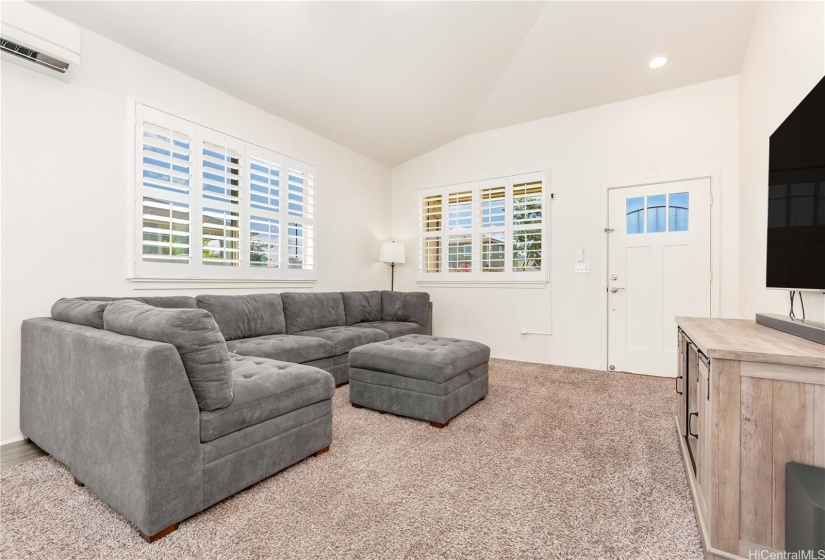 Living room with a vaulted ceiling. (Vinyl plank flooring below large area carpet)