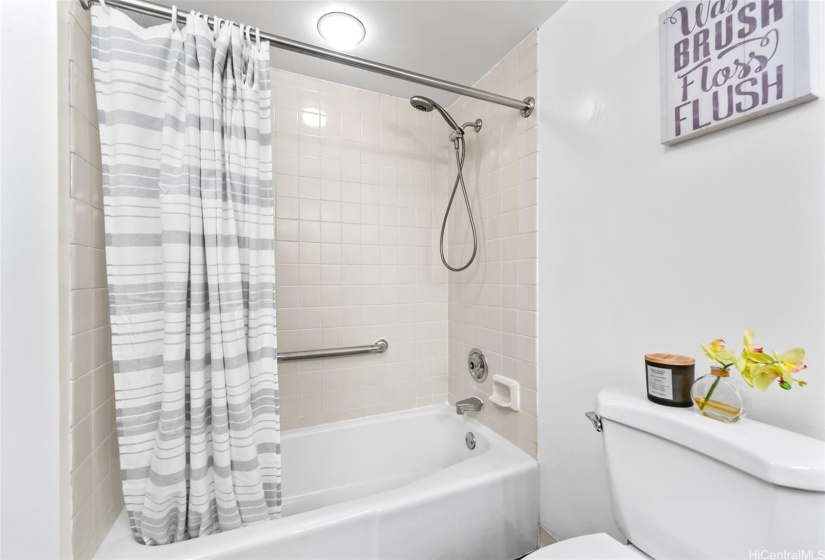 Bathroom has a standard sized tub and shower nozzle