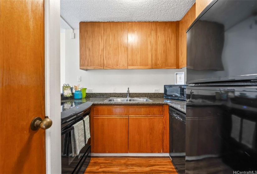 Kitchen is stocked with range top, refrigerator and dishwasher