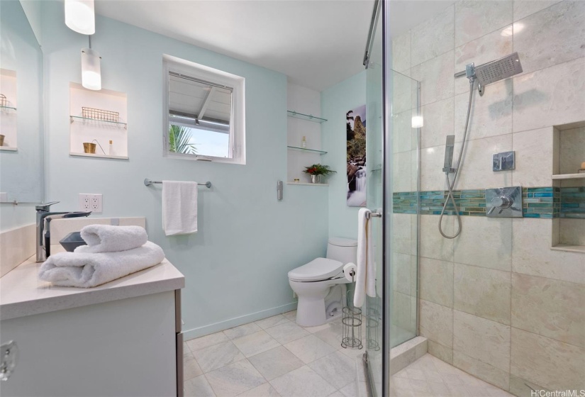 Main home features this beautifully remodeled bathroom with marble tile and custom glass shower enclosure.