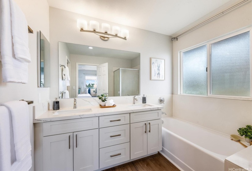 Primary bath with his and hers sinks, tub, and shower