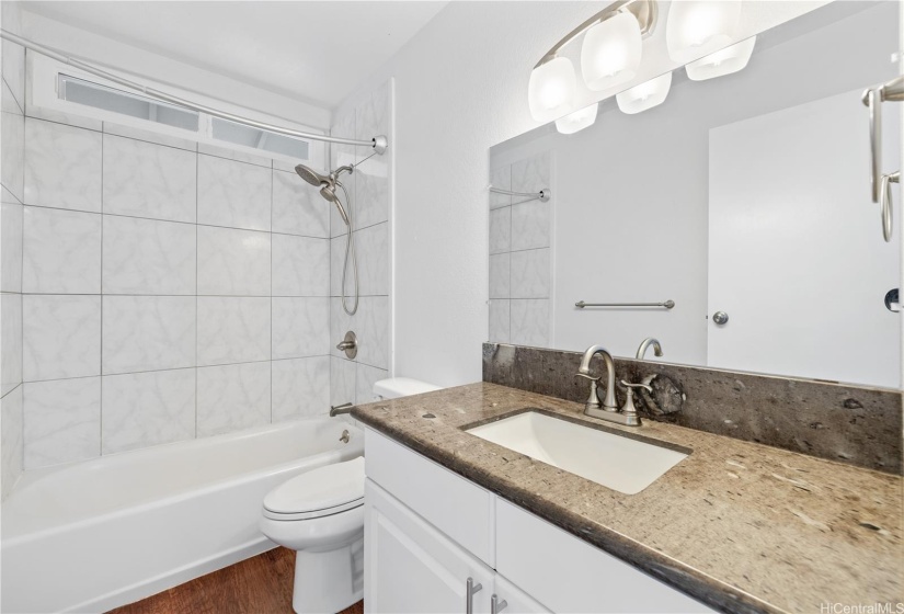 Hallway bath with granite counter tops and hardwood cabinets.