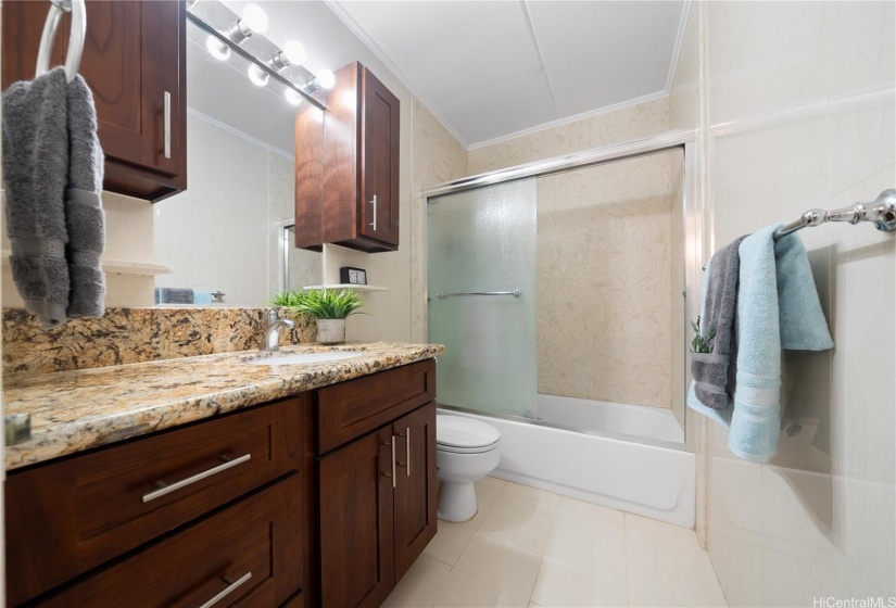 Guest Bathroom features tiled wall and surround with plenty of storage.