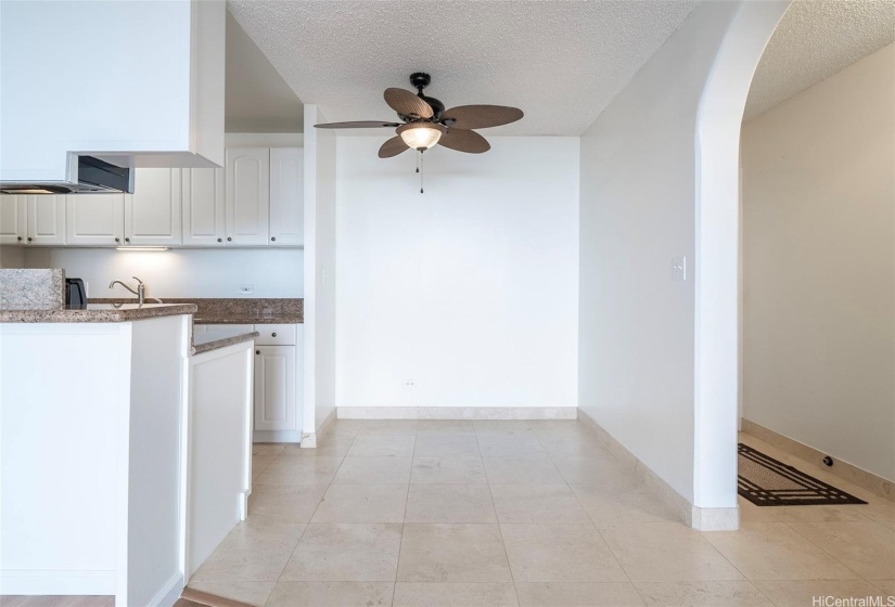 Dining area with ceiling fan lighting. Arched entry hallway to the right.