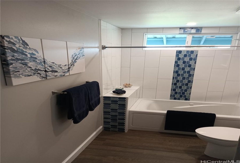 Bathroom #2 showing tub / shower, with vertical blue tile strip on the wall.