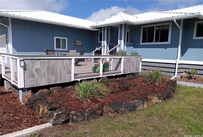 Tiled planters at front of home, rock lined planter beds in foreground and front porch.