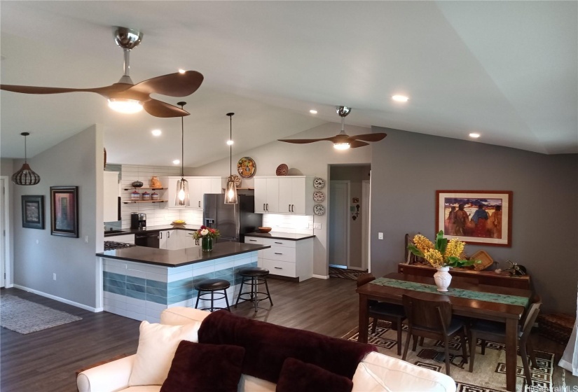 Distance shot of kitchen on left, dining table on the right, white couch in foreground.