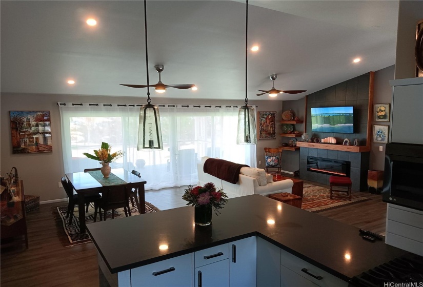 Main living area, dining set on left, TV and fireplace on right, kitchen counter in foreground.