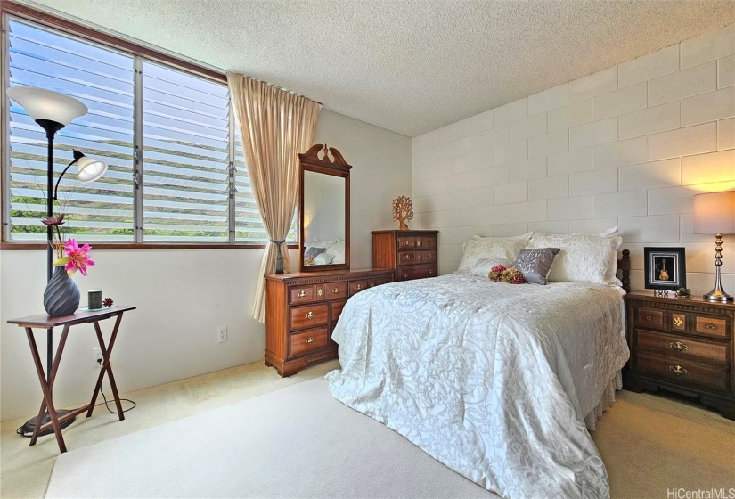 Enjoy cool breezes with lush treetop views from this primary bedroom!