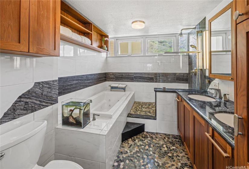 Primary bath features an oversized Jacuzzi tub and luxury tiling