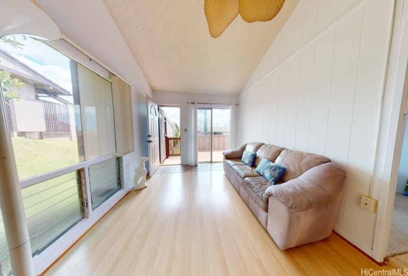 Another view of the living room showing the  large windows, sliding door and front door