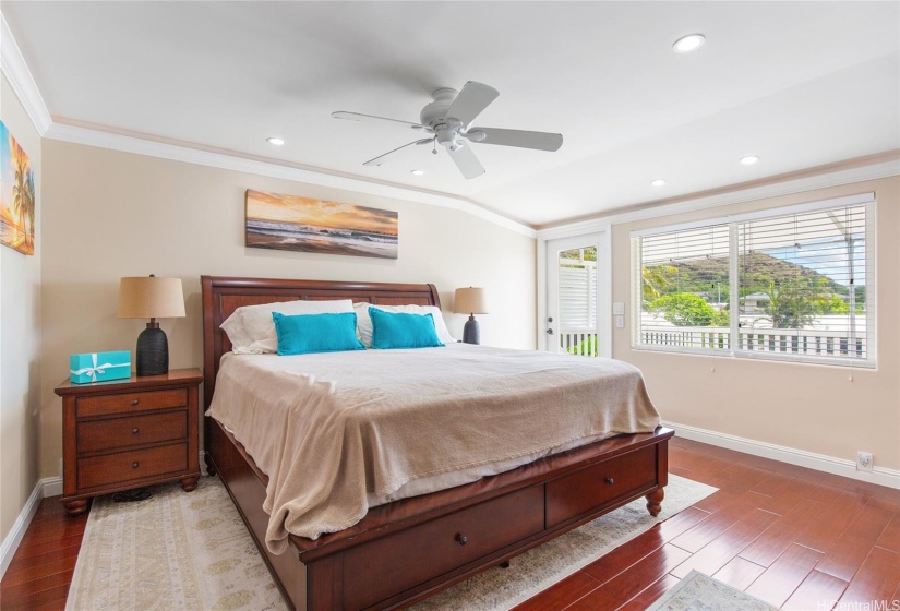 Upstairs primary bedroom with hardwood flooring and water view