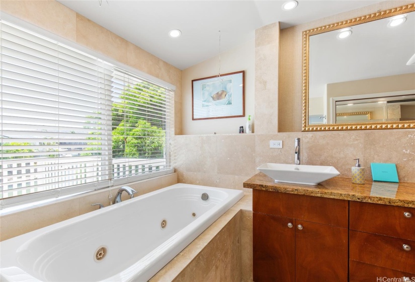 Primary bathroom with jacuzzi tub and travertine stone all throughout.