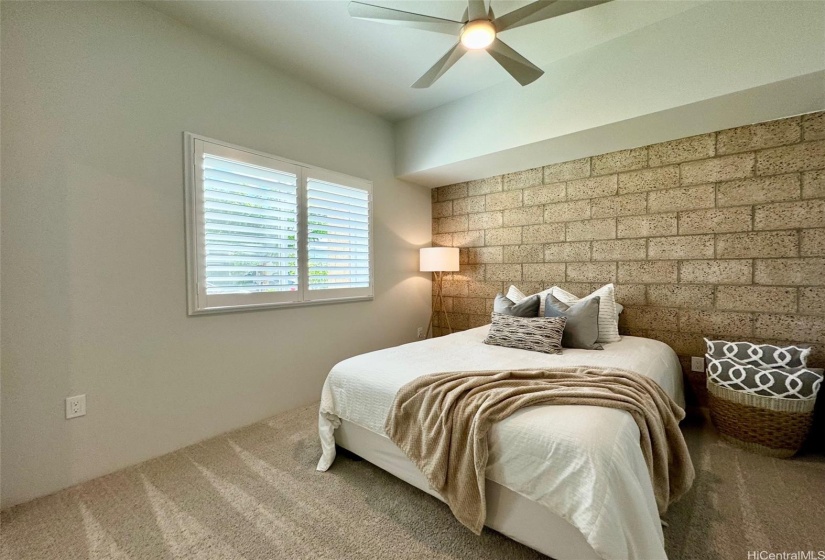 BEDROOM FEATURING PLANTATION SHUTTERS, MODERN CEILING FAN, & AN URBAN CHIC ACCENT WALL