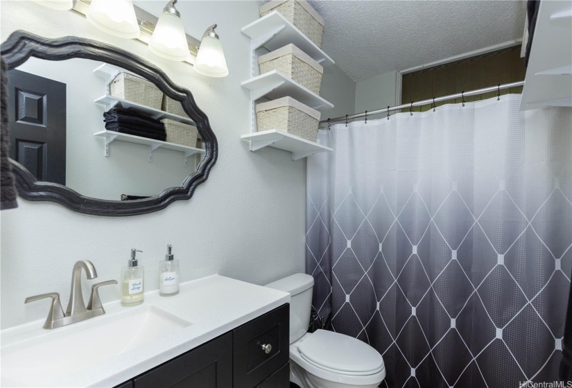 Updated bathroom with new vanity, granite counter, decorative mirror, and fixtures.