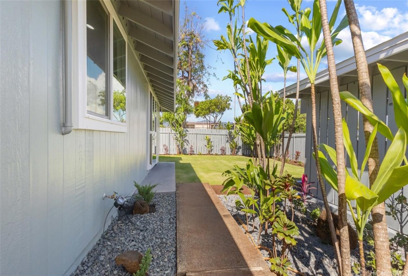 Backyard walkway view with carport on the right side.