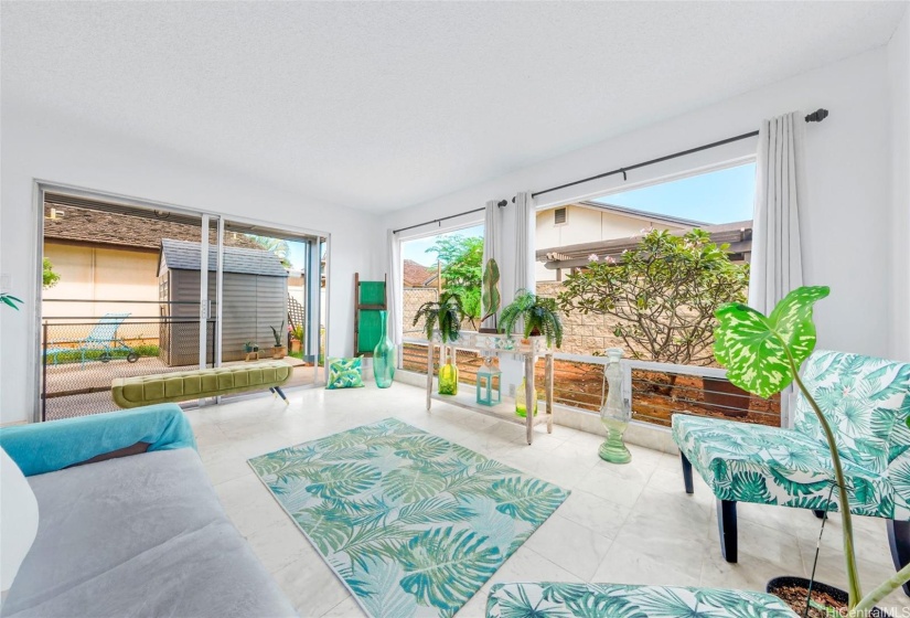 ENHANCED:  Living room goes out into the lanai sliding doors and the backyard wraps to the right with a plumeria tree.