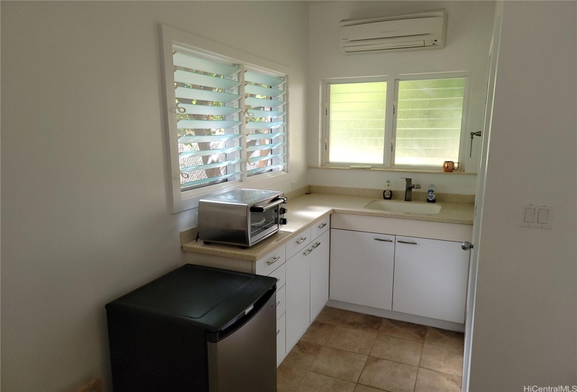 The kitchenette area, with sink, oven and apt sized fridge, and a/c over the window.