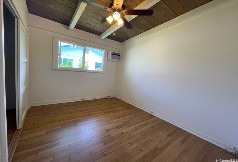 Bedroom 2 with window AC unit and ceiling fan.