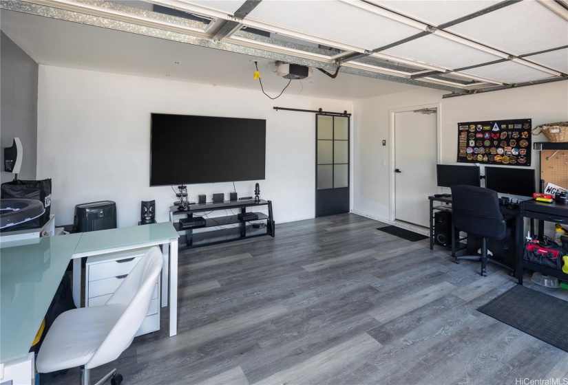 Garage with Tesla Level 2 Charger. The water heater and storage area are behind a stylish shoji-type door.