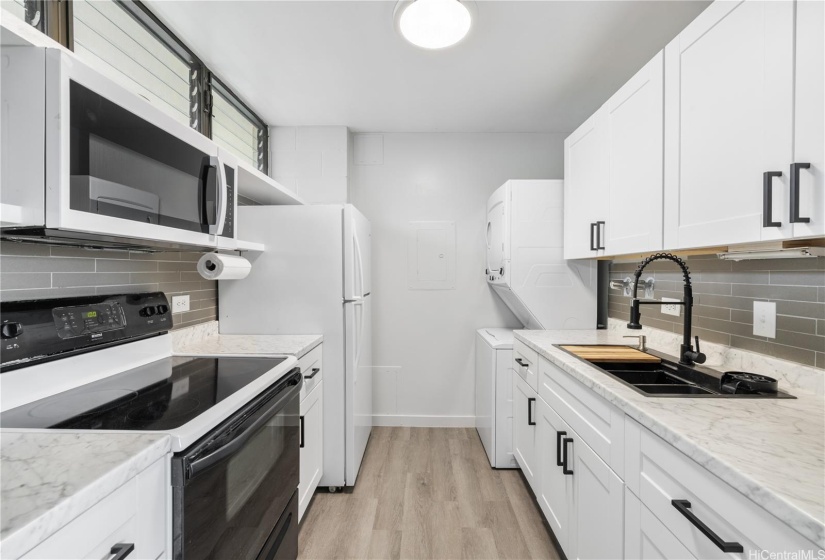 Fully remodeled galley kitchen with updated cabintry, countertops, microwave and sink with butcher block.
