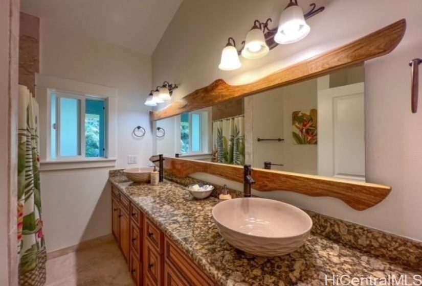 Wood framed mirror goes the full lenght of the guest bathroon that also includes a stacked washer and dryer.