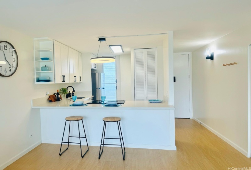 Absolutely move in ready! This modern black and white designed kitchen is beautiful and functional. Accordion style pantry closet offers even more storage options. The sleek white quartz countertops were extended out to create an optional dining area. Luxury vinyl planks were installed with double the recommended underlayment to ensure minimum sound transfer (flooring and popcorn ceiling are all board approved, compliant, & documented) Newly painted ceiling, interior, and lanai welcomes you home to a new beginning.  New baseboards were installed throughout the unit. Additional wooden bag hooks were installed on the entrance wall to enhance functionality and design.