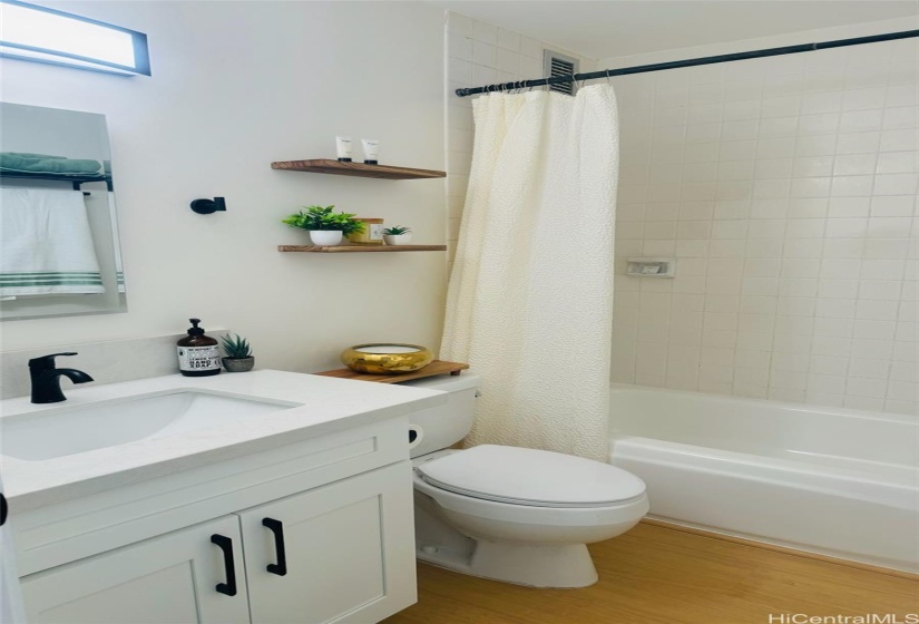 Beautifully remodeled bath w all new vanity, fixtures, additional wood shelving, matching black towel rack and towel hooks offer convenience and additional function.