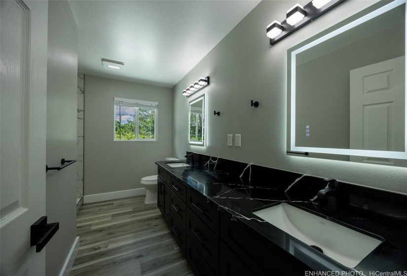 Primary bathroom with its stunning countertop, dual sinks and enhanced lighting...