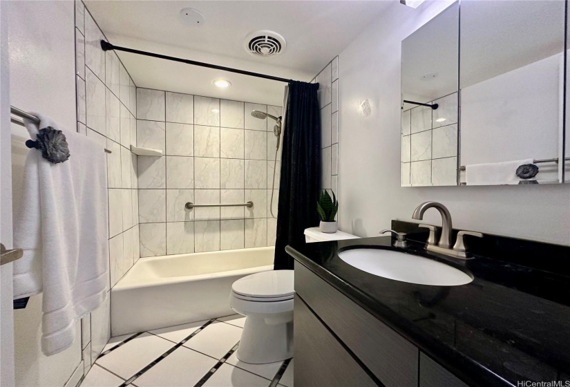 Ceramic tiled bathroom with black countertop brings a modern look.