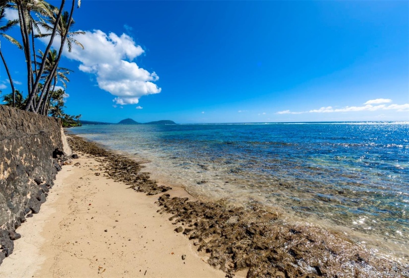 Tranquil ocean and partial sandy beach frontage.