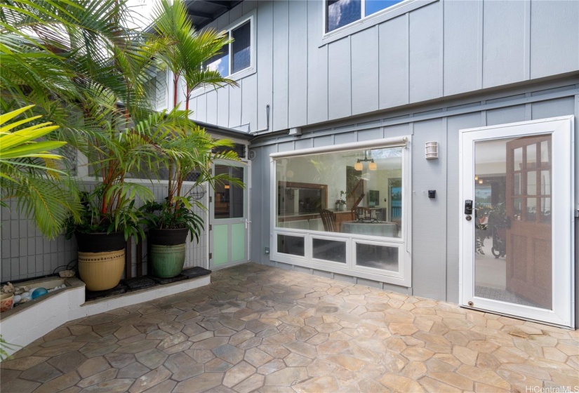 Tropically landscaped and private front courtyard,   Door to left accesses laundry/mud/storage room; door to right enters to living room.