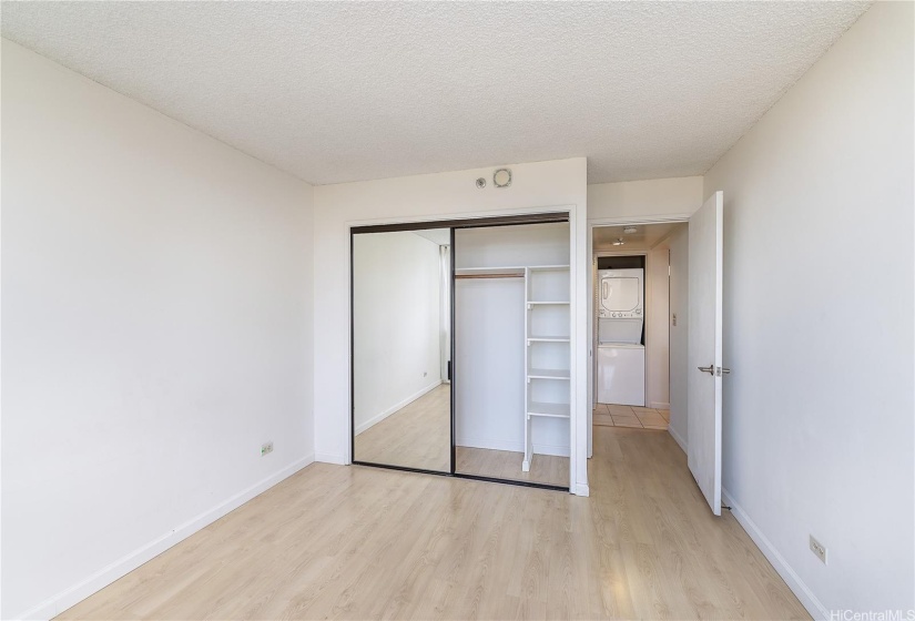 Gust bedroom closet with built in shelving and view into the hallway with guest bathroom leading to laundry and kitchen area