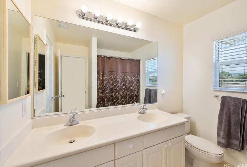 Primary bathroom with dual sinks and tub/shower combination.