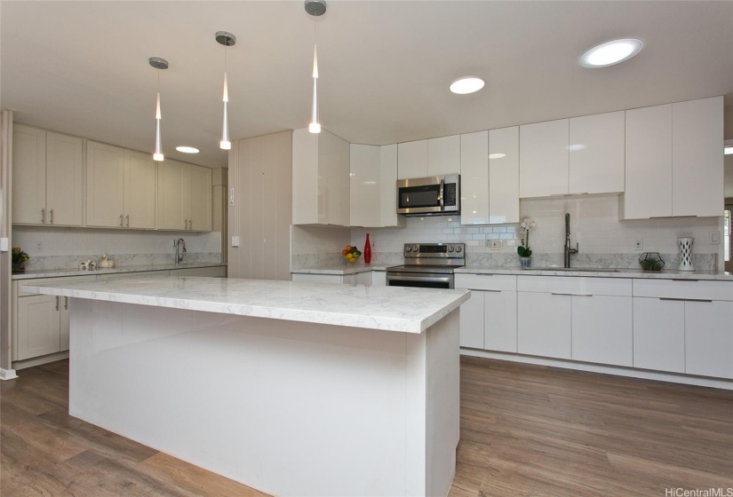 Beautiful kitchen features stunning white cabinets along with marble countertops and backsplash