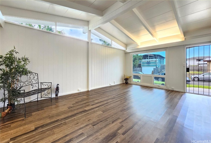 The living room features open beam ceilings and a security screen door.