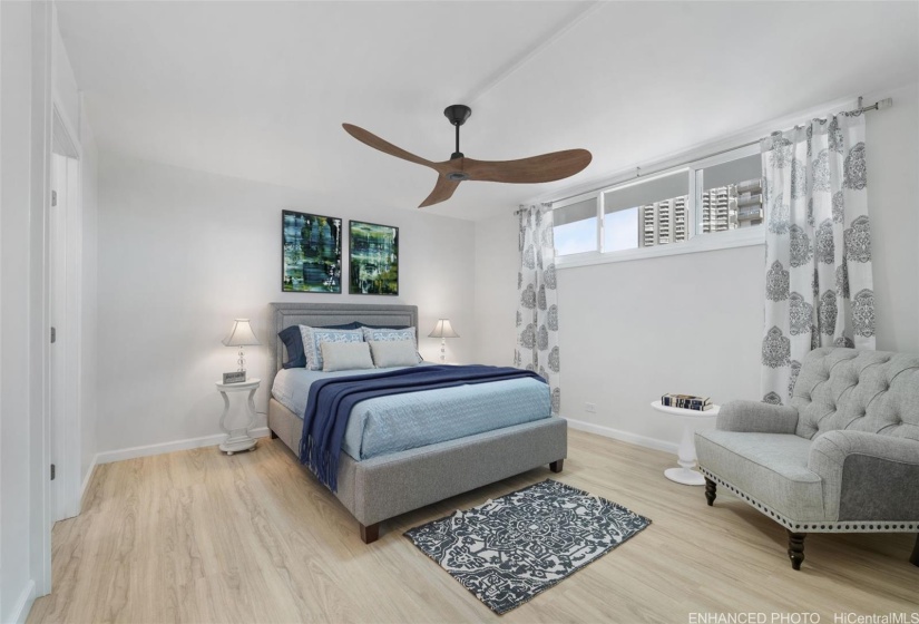 Partially enhanced mauka (mountainside) en suite bedroom with ceiling fan and wall art. Furnishings are negotiable.