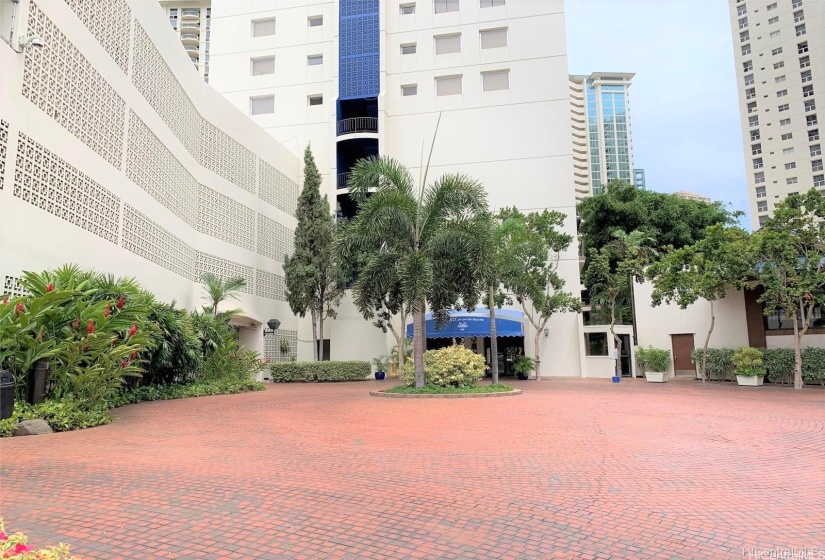 Front of building with large driveway and private garage entry for residents